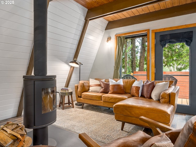 living room featuring beam ceiling, a wood stove, wood walls, and wooden ceiling