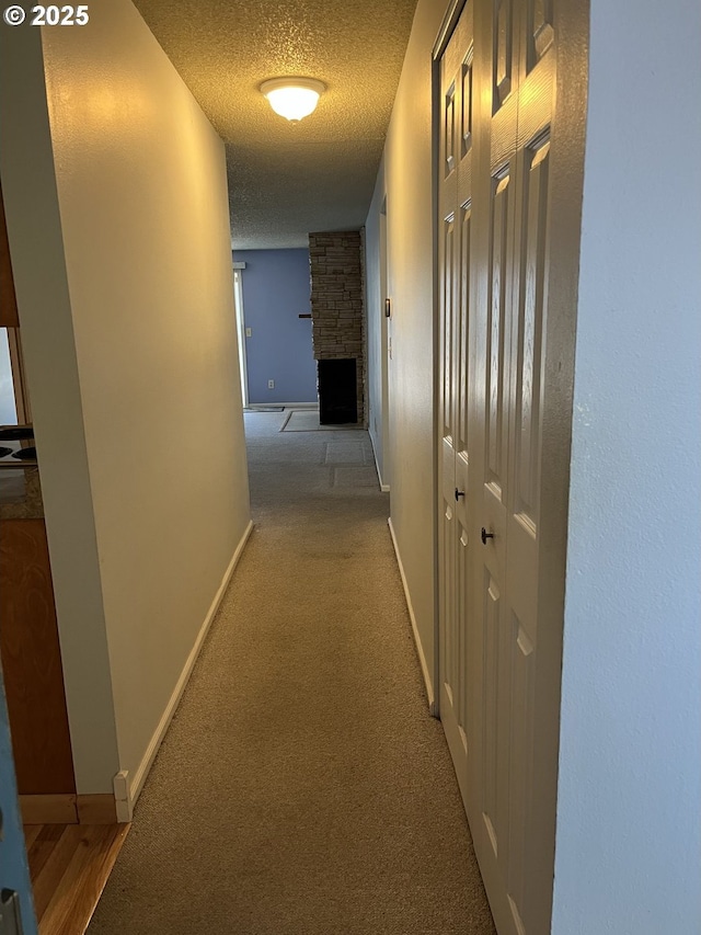 hallway featuring a textured ceiling and light carpet