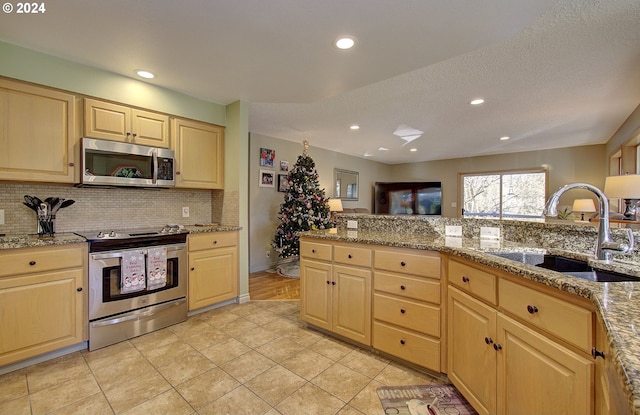 kitchen with sink, a textured ceiling, light brown cabinetry, appliances with stainless steel finishes, and light stone counters