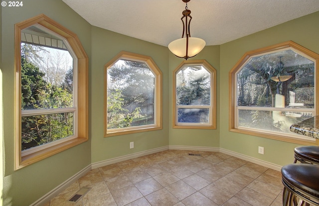 unfurnished dining area featuring light tile patterned flooring, a textured ceiling, and a wealth of natural light