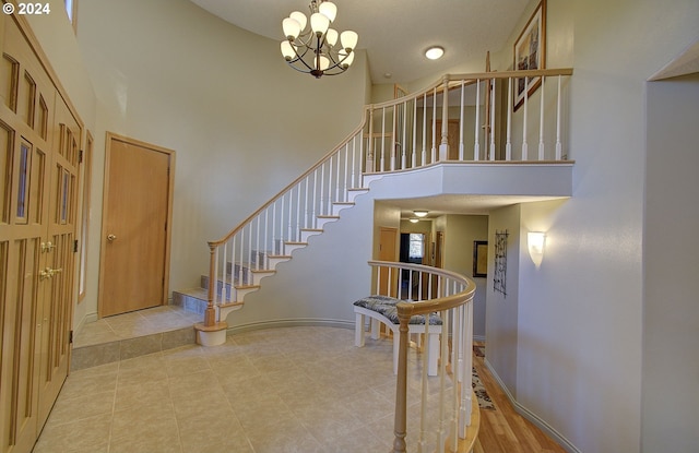 staircase with a notable chandelier and a towering ceiling