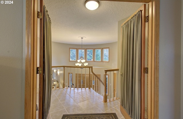 hallway with a chandelier, light tile patterned floors, and a textured ceiling