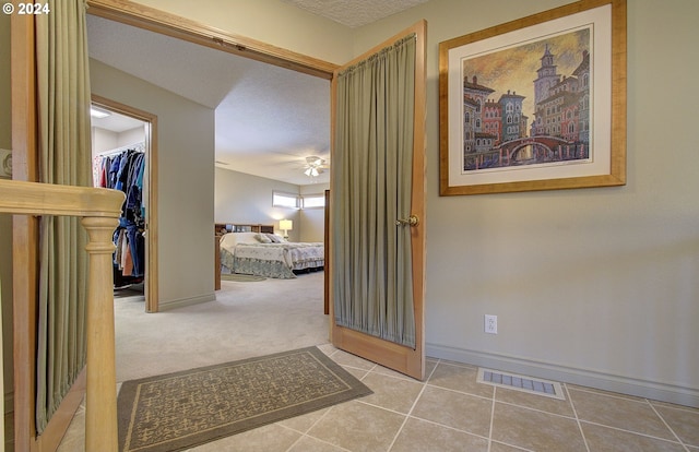 hallway featuring a textured ceiling and light colored carpet