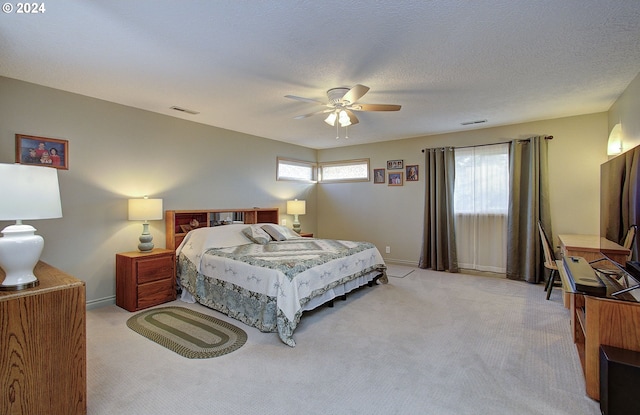 bedroom featuring ceiling fan, light colored carpet, and a textured ceiling