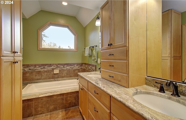 bathroom with tile patterned floors, vanity, tiled tub, and vaulted ceiling