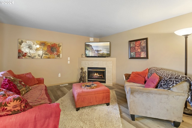 living room with wood-type flooring and a tile fireplace