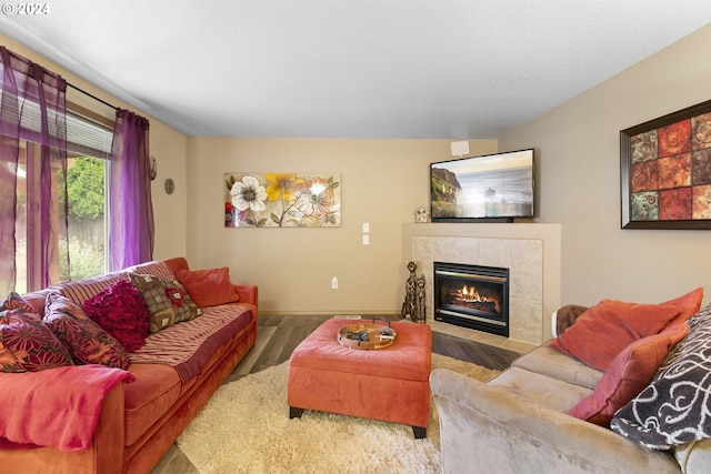 living room with a tile fireplace and hardwood / wood-style flooring