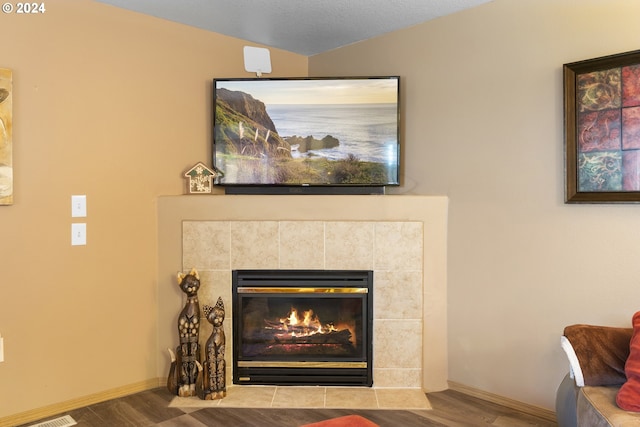 details with a textured ceiling, a tile fireplace, and wood-type flooring