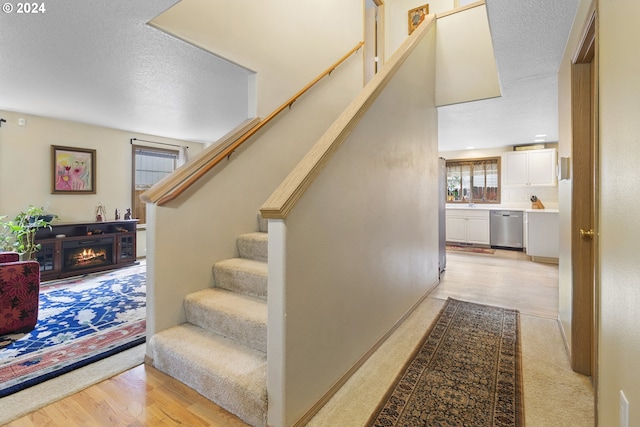 stairway with wood-type flooring, a textured ceiling, and sink