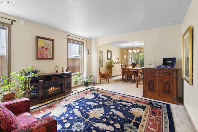 living room featuring a textured ceiling, light carpet, and a notable chandelier