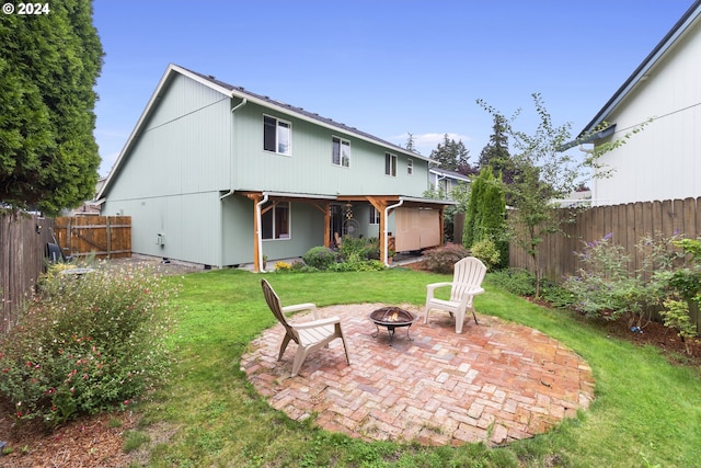 rear view of house featuring a fire pit, a lawn, and a patio