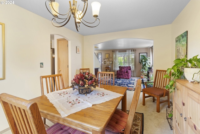 dining room with light carpet and a notable chandelier