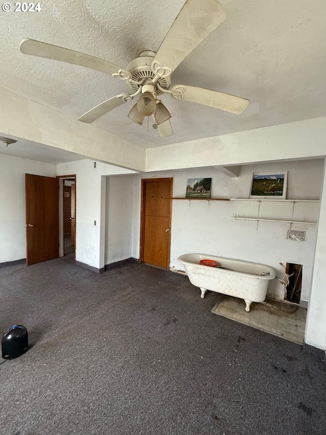 unfurnished bedroom featuring dark colored carpet, a textured ceiling, and ceiling fan