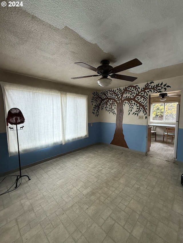 unfurnished room with ceiling fan and a textured ceiling