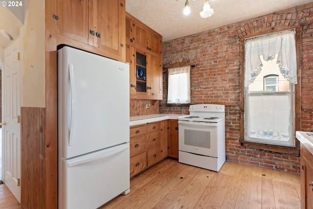 kitchen featuring light hardwood / wood-style floors, brick wall, and white appliances