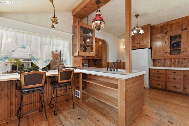 kitchen with light hardwood / wood-style flooring, kitchen peninsula, vaulted ceiling, a chandelier, and white fridge