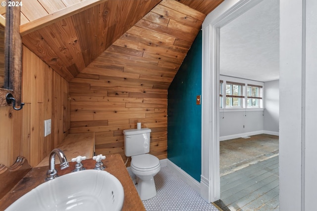 bathroom with sink, toilet, wood walls, and lofted ceiling