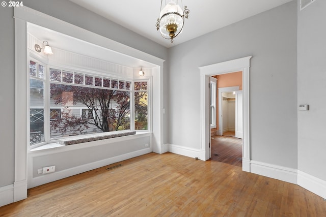 unfurnished dining area featuring hardwood / wood-style flooring and an inviting chandelier