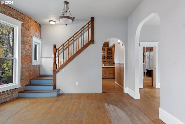 staircase with brick wall and wood-type flooring