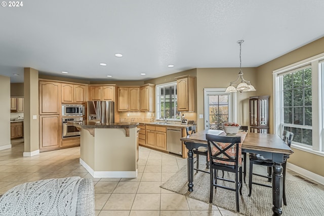 kitchen featuring appliances with stainless steel finishes, light tile patterned flooring, a breakfast bar, pendant lighting, and a center island