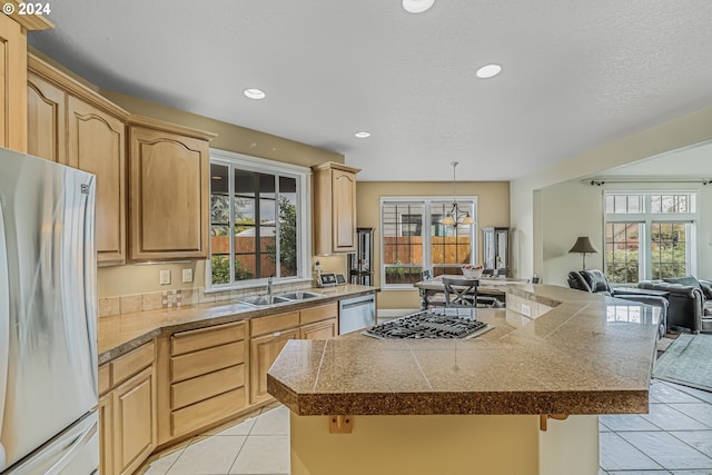 kitchen featuring light brown cabinetry, appliances with stainless steel finishes, sink, and a wealth of natural light