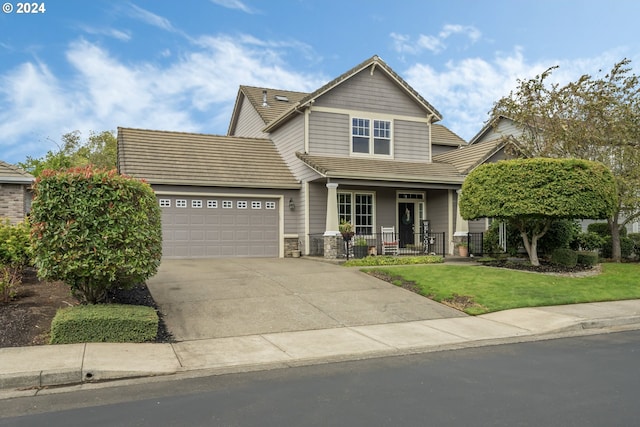 view of front of property featuring covered porch, a front yard, and a garage