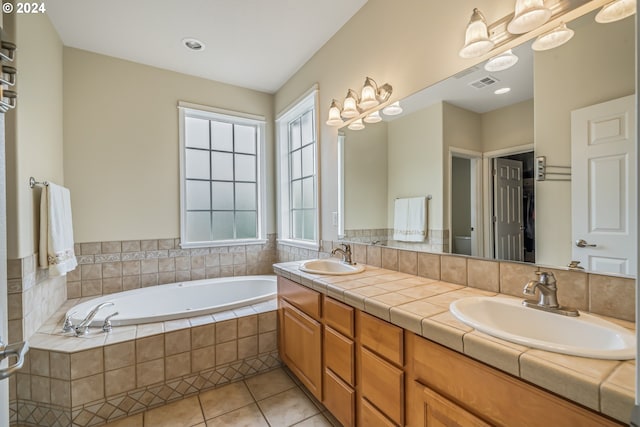 bathroom with vanity, tile patterned flooring, a relaxing tiled tub, and toilet