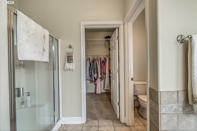 bathroom with a shower with door, vanity, and tile patterned floors