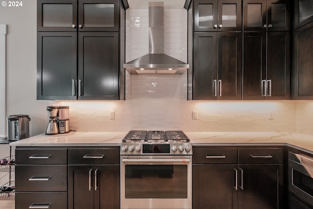 kitchen with stainless steel range with gas cooktop, tasteful backsplash, wall oven, dark brown cabinetry, and wall chimney range hood