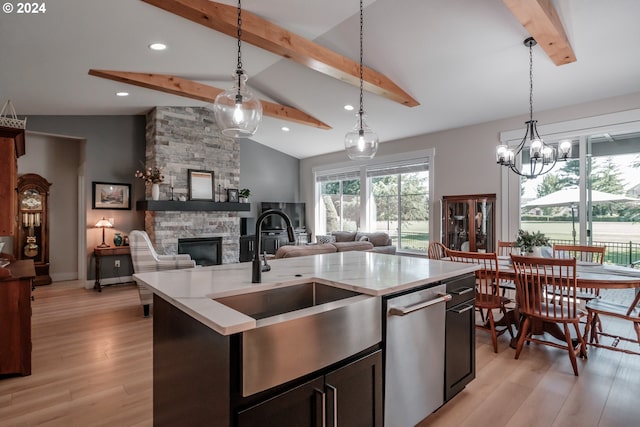 kitchen featuring pendant lighting, sink, a fireplace, and an island with sink