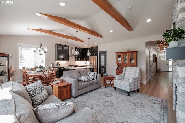 living room featuring sink, a chandelier, lofted ceiling with beams, and light hardwood / wood-style flooring