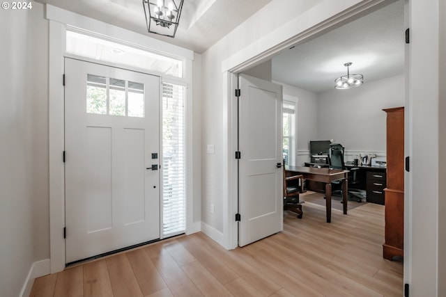 entrance foyer featuring a wealth of natural light, an inviting chandelier, and light hardwood / wood-style flooring