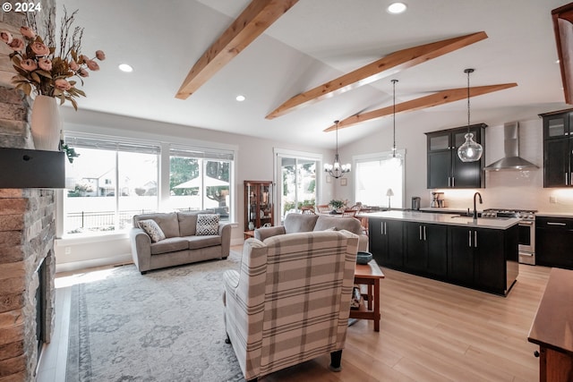 living room with plenty of natural light, a stone fireplace, light hardwood / wood-style floors, and vaulted ceiling with beams