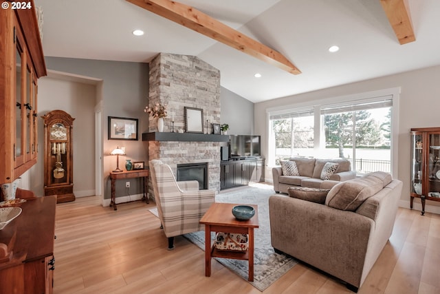 living room featuring vaulted ceiling with beams, a stone fireplace, and light hardwood / wood-style floors