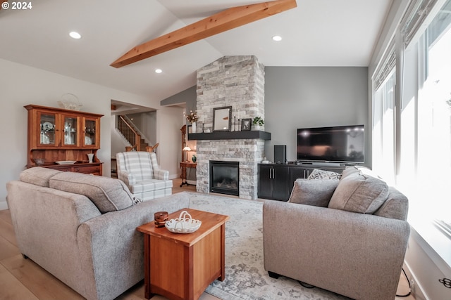 living room with a fireplace, lofted ceiling with beams, light hardwood / wood-style floors, and a healthy amount of sunlight