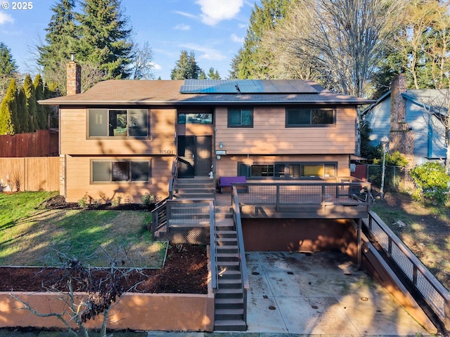 rear view of house with a yard, a patio, a deck, and solar panels