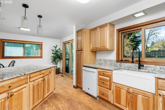 kitchen with light stone countertops, sink, white dishwasher, decorative light fixtures, and light wood-type flooring