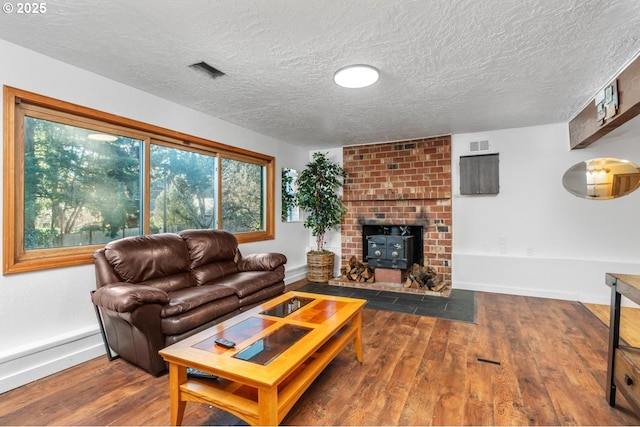 living room with a textured ceiling, dark hardwood / wood-style flooring, and a wood stove