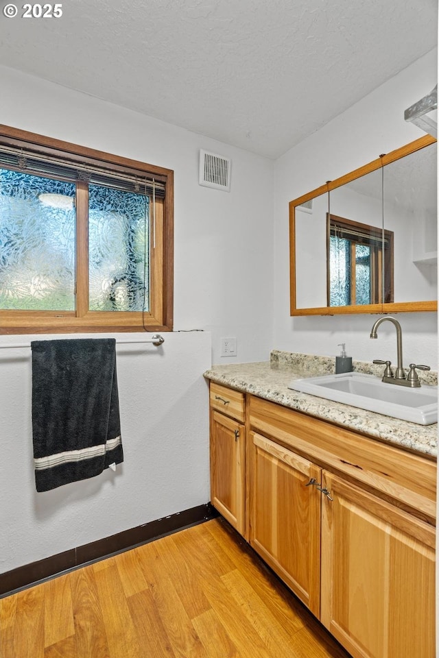 bathroom featuring wood-type flooring, vanity, and a textured ceiling