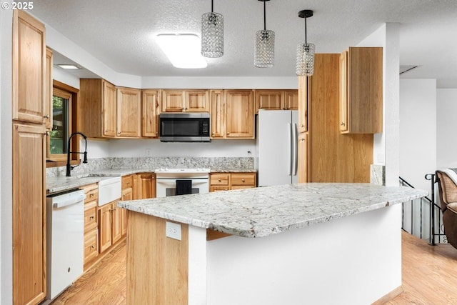 kitchen featuring decorative light fixtures, light hardwood / wood-style floors, white appliances, and a textured ceiling