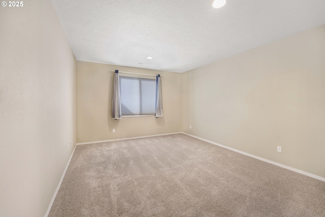 empty room featuring a textured ceiling, recessed lighting, carpet flooring, and baseboards