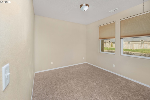 carpeted spare room featuring visible vents and baseboards