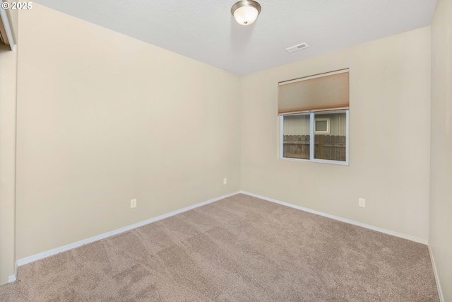 spare room with a textured ceiling, carpet floors, and baseboards