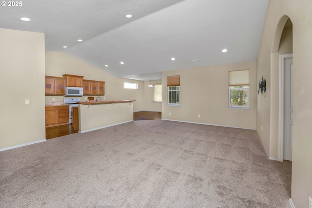 living room featuring lofted ceiling, arched walkways, recessed lighting, baseboards, and carpet