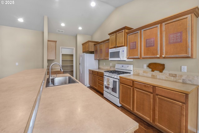 kitchen with lofted ceiling, white appliances, a sink, visible vents, and dark wood-style floors