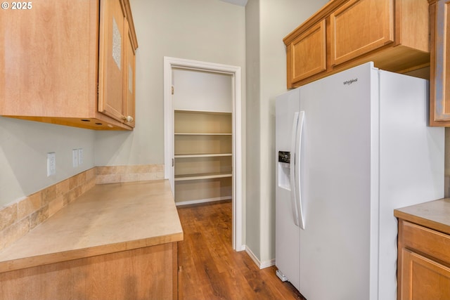 kitchen featuring brown cabinets, white refrigerator with ice dispenser, light countertops, and dark wood-style flooring