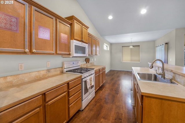 kitchen with brown cabinets, white appliances, light countertops, and a sink