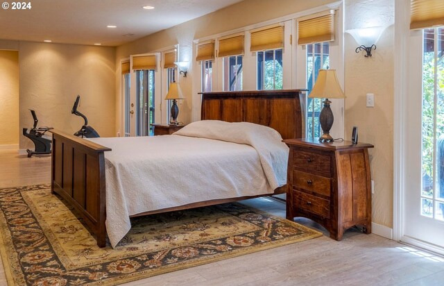 bedroom with light wood-type flooring, access to exterior, and multiple windows