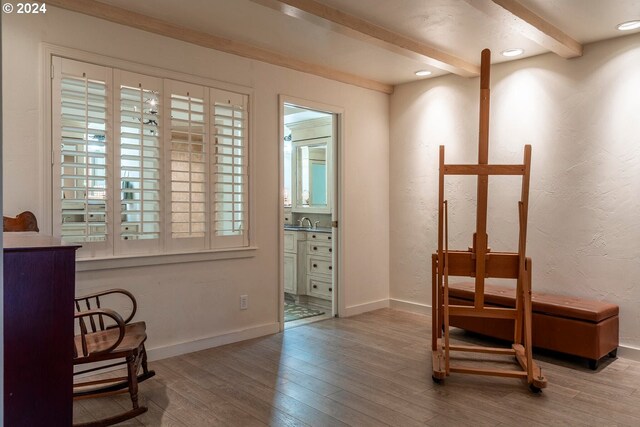 sitting room with light wood-type flooring, beamed ceiling, and sink