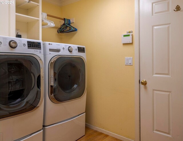 laundry room with washing machine and clothes dryer and light hardwood / wood-style flooring